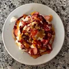A plate topped with fruit, cream and nuts at Café Clara in Munich